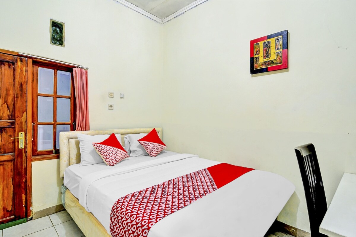 Une chambre à coucher avec un lit, une porte en bois, une fenêtre avec des rideaux et un tableau accroché au mur.