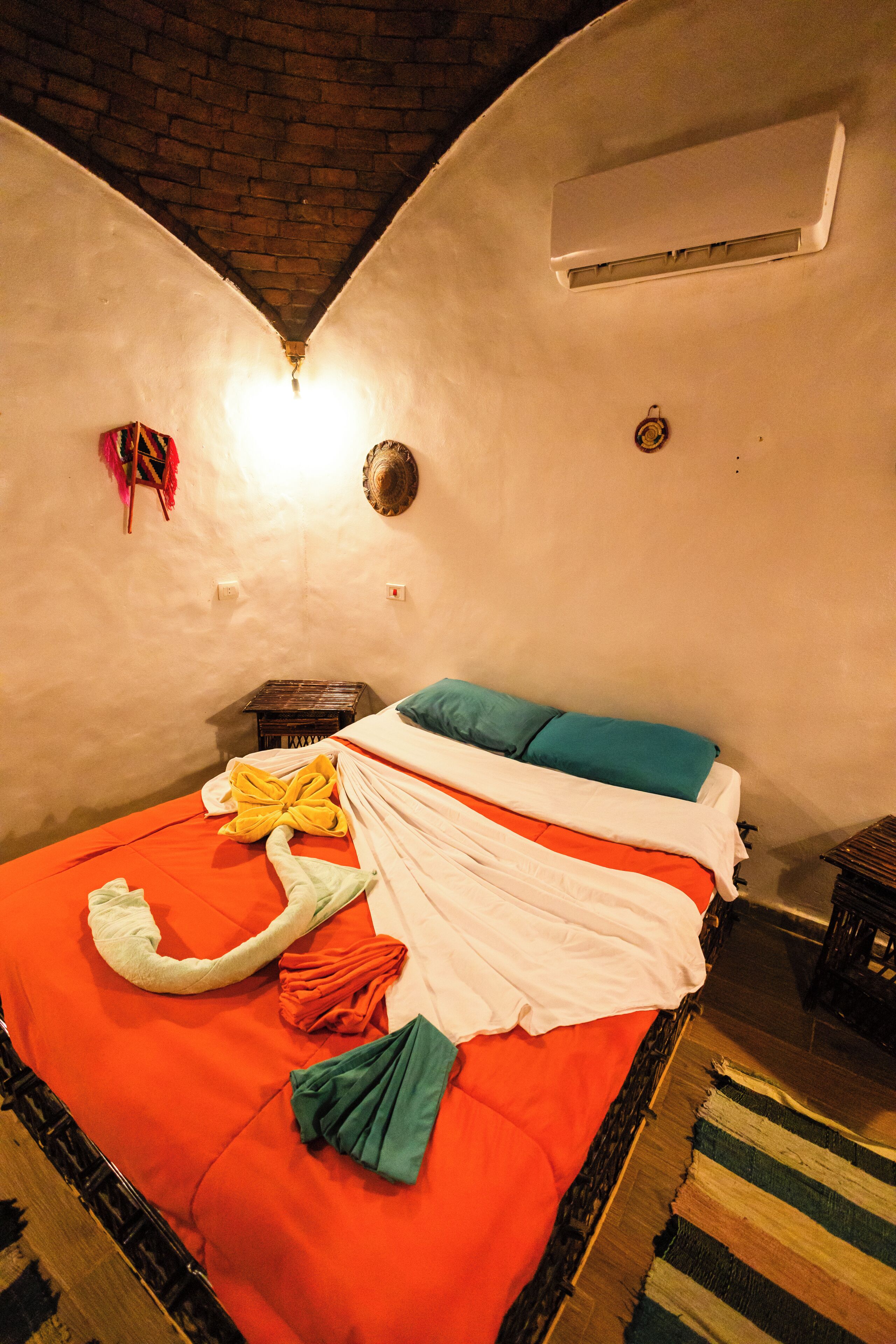 Una habitación con una cama, una mesita pequeña y aire acondicionado de pared.