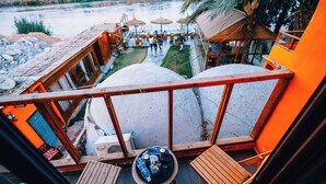 Ein Balkon mit Holzmöbeln, einem Tisch mit Getränken und Blick auf einen Poolbereich.