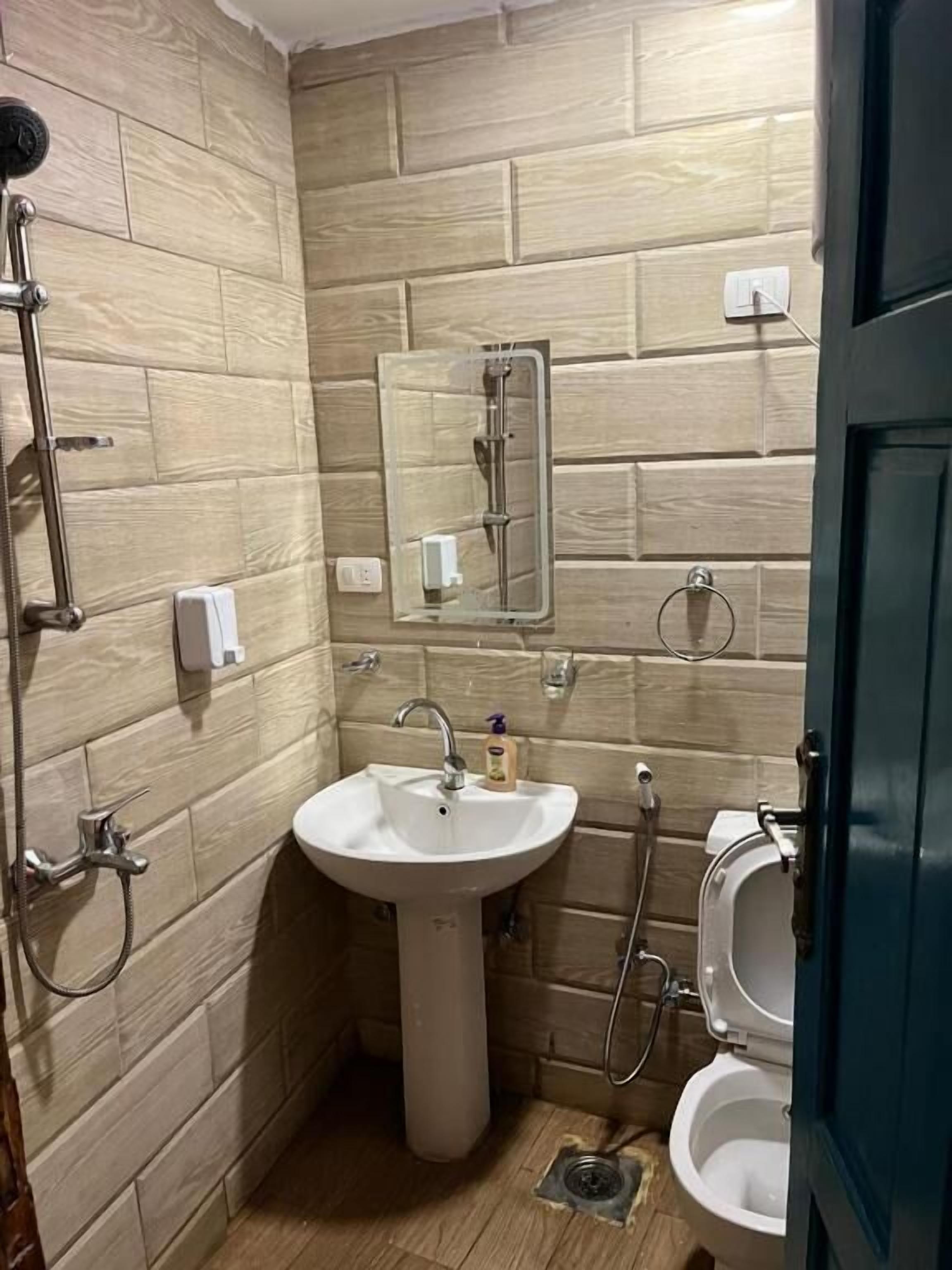 Une salle de bain équipée d’un lavabo sur colonne, d’un miroir, de toilettes et d’une cabine de douche.