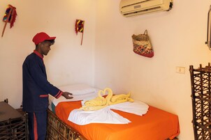 Una habitación de hotel con una cama, un maletero y un aire acondicionado instalado en la pared.