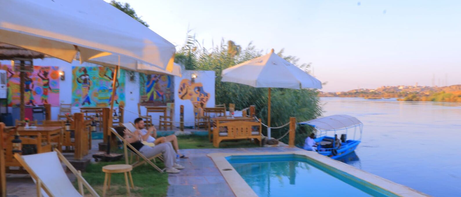 A poolside area with wooden furniture and a mural on the wall.