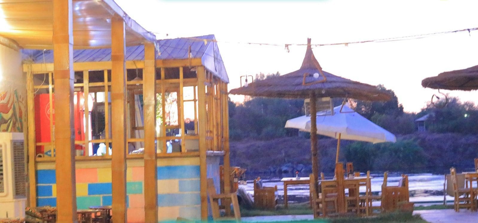 A building with a colorful exterior, outdoor seating, and a shaded area with umbrellas.