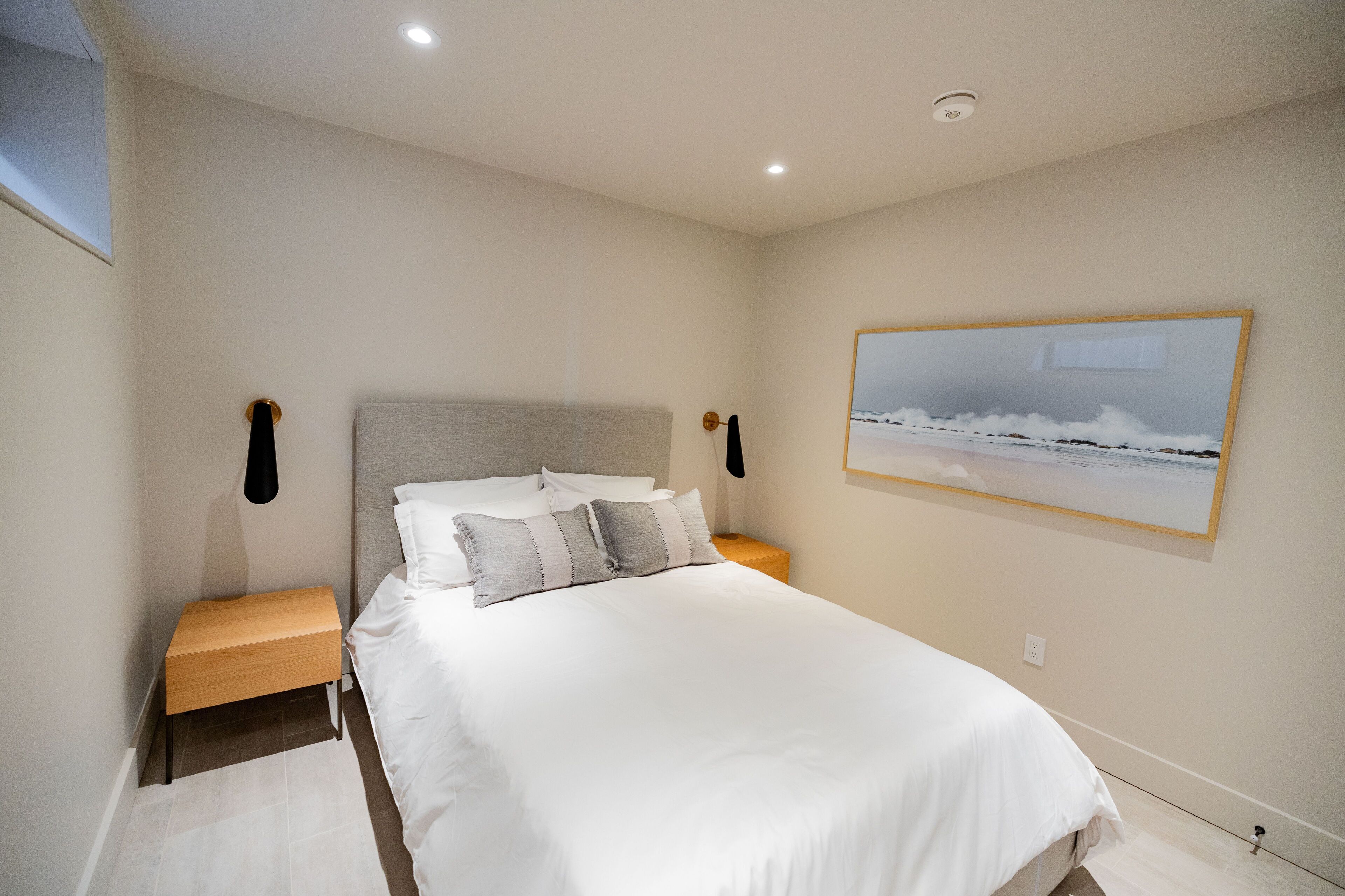 A bedroom with a bed, nightstands, a headboard, and a painting on the wall.
