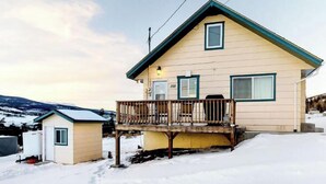 Ett tvåvåningshus med en balkong, ett litet uthus som sitter ihop med huset och ett snötäckt landskap.