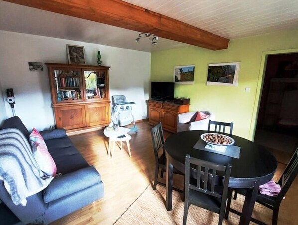 Un salon confortable avec un canapé, une table à manger, des chaises, un téléviseur et un meuble.