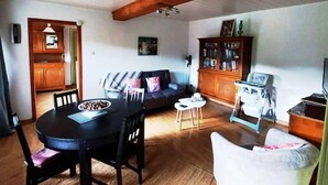 A cozy living room with a dining table, chairs, a sofa, and a television. - Chez Nadine (Ranspach)