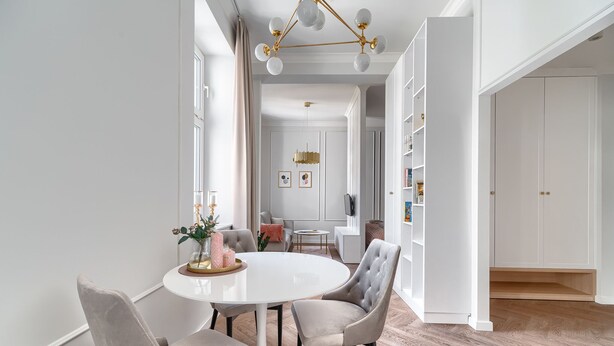 Een moderne eetruimte met een witte tafel, grijze bekleden stoelen en een decoratief middelpunt.