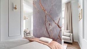 Een moderne hotelkamer met een groot bed, een zithoek en een wand bekleed met marmer.