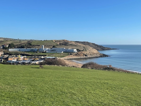 A coastal hotel with a large building, a grassy foreground, and a view of the sea. - The White House (Weymouth)