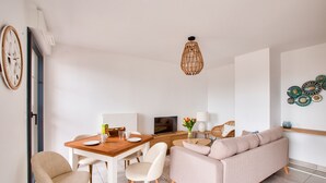 Un salon moderne avec une table à manger en bois, un canapé beige et un téléviseur.