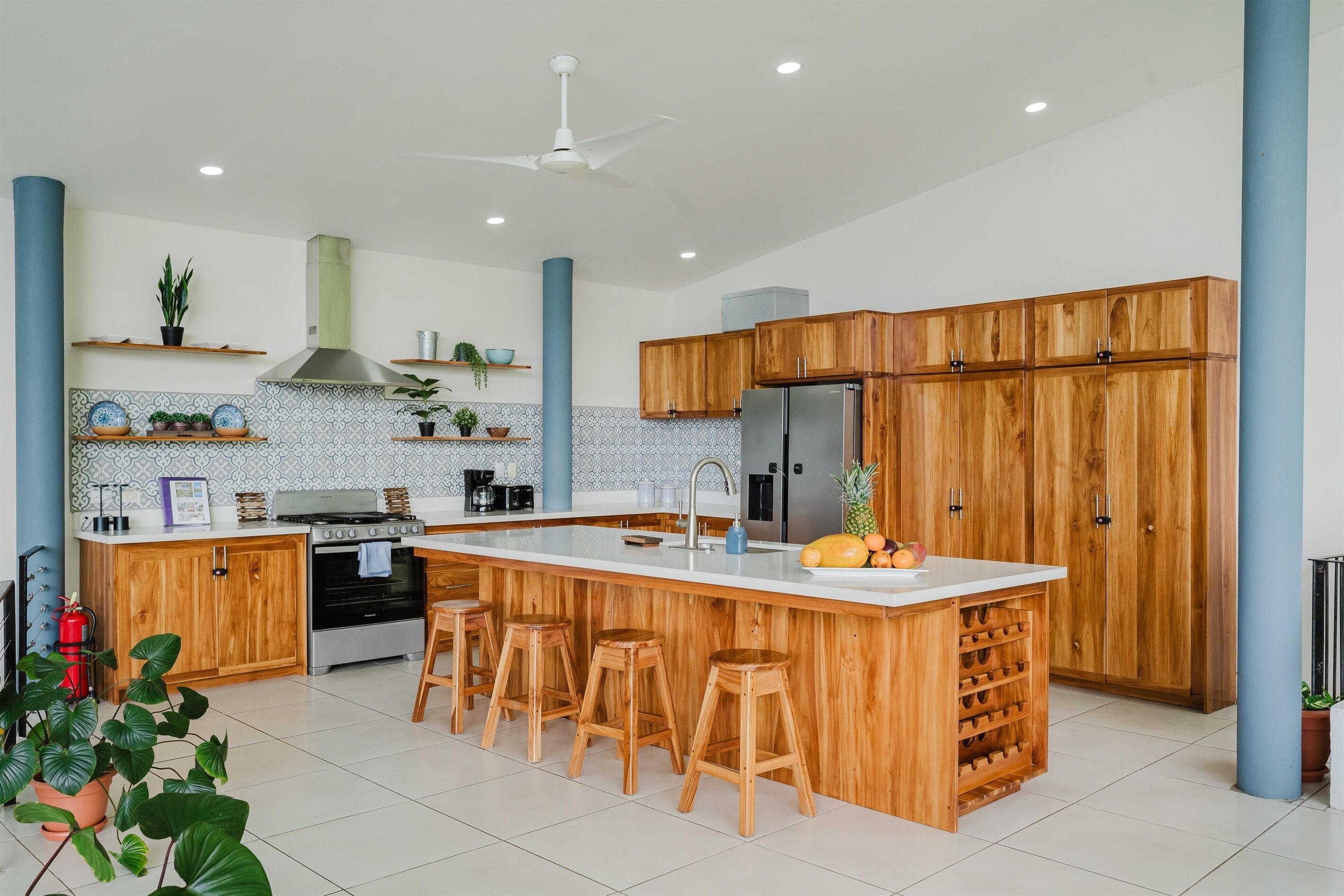 Una cocina moderna con una isla central, armarios de madera y taburetes de bar.