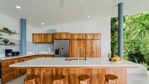 Una cocina moderna con armarios de madera, una isla grande con taburetes y vistas a espacios verdes.