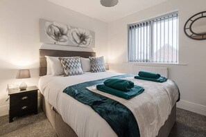Cozy retreat with a large bed, nightstand, and artwork.