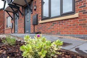 Stunning residential building with a modern design, featuring a dark door and windows with black frames, set amidst a charming garden.