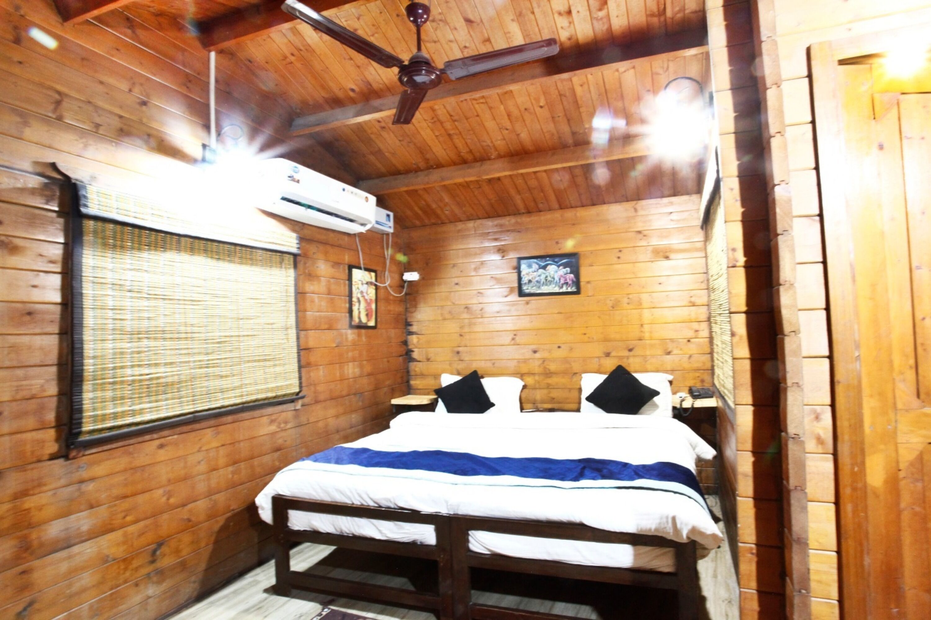 Una habitación de cabaña de madera con cama, ventilador de techo y aire acondicionado.