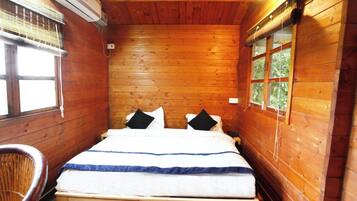 Un dormitorio de cabaña de madera con una cama, almohadas, una silla y una ventana.