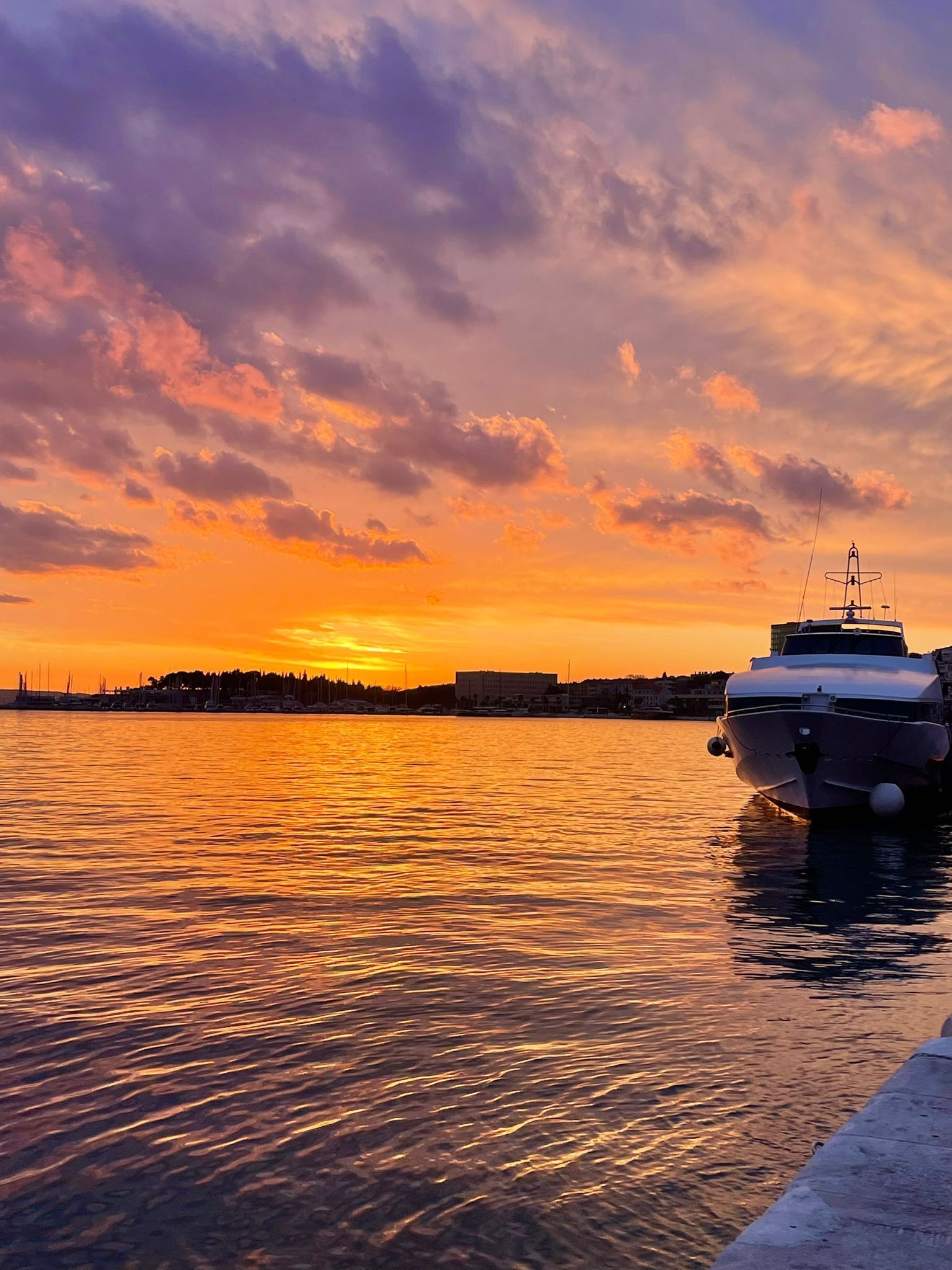 A boat docked at a pier during sunset.