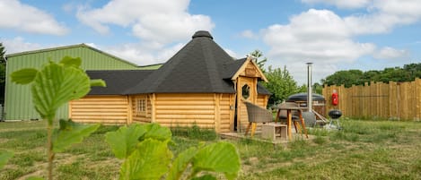 A wooden cabin with a sloped roof, a small porch, and a chimney.