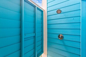 Una puerta de madera turquesa con un tirador de metal y una rejilla circular.