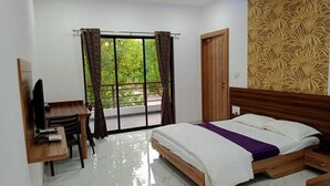 A bedroom with a bed, a desk, a television, and a window with curtains. - D Star Entertainment Water ParkAndResort (Chiplun)
