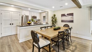 A modern kitchen with white cabinetry, stainless steel appliances, and a wooden dining table with six chairs. - Recently updated Palmetto Dunes villa with fairway views and community pools. (Hilton Head Island)