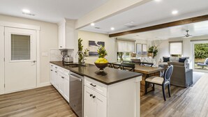 A modern kitchen with white cabinetry, a central island, and a dining area with a table and chairs. - Recently updated Palmetto Dunes villa with fairway views and community pools. (Hilton Head Island)
