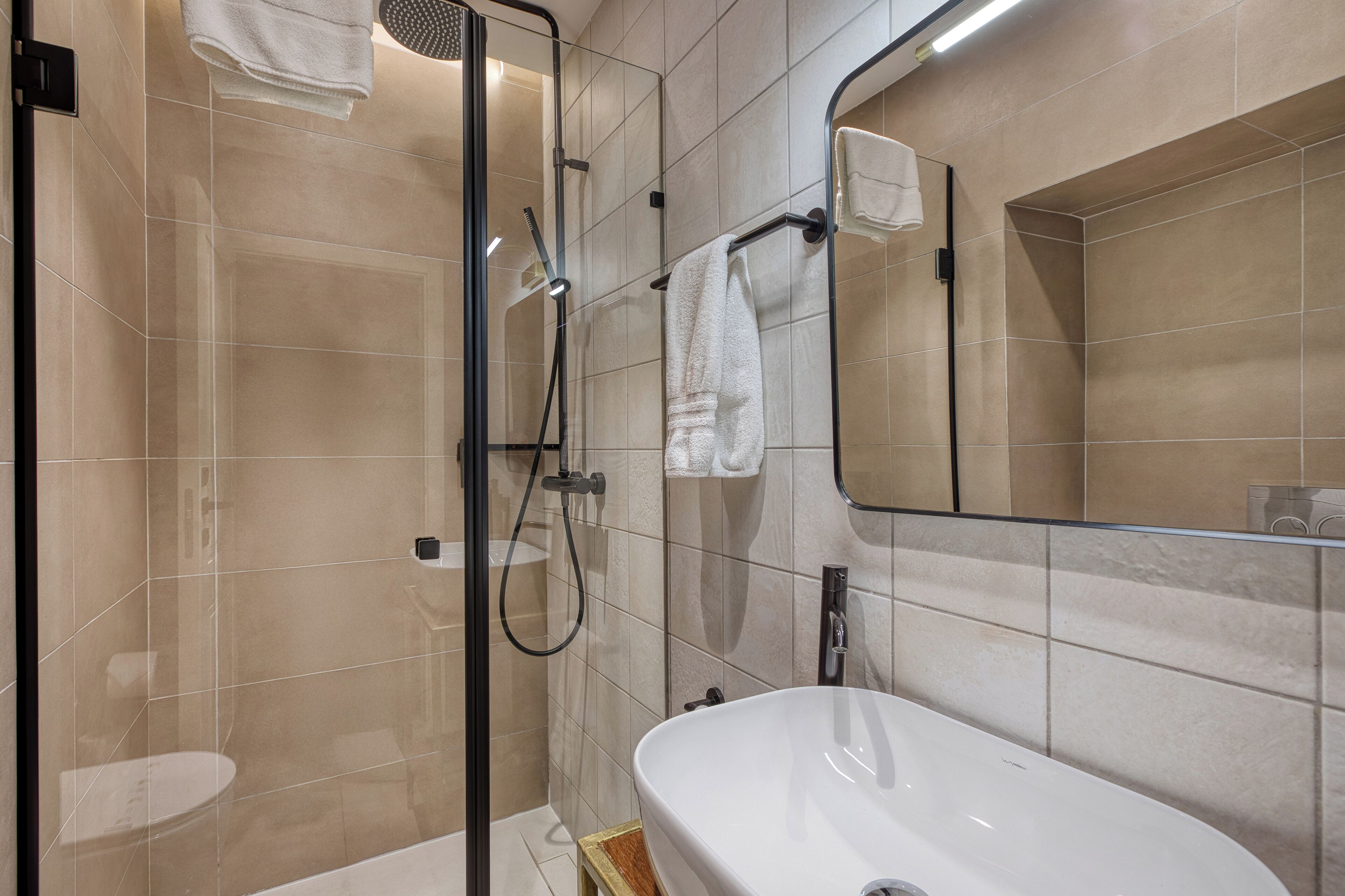 Une salle de bain moderne avec une douche à parois de verre, un lavabo blanc et un grand miroir.