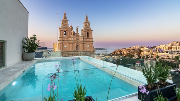 Piscina en la azotea con vistas a una iglesia histórica y al paisaje urbano.
