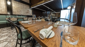 Un restaurante con mesas de madera, asientos tapizados en verde y un suelo estampado.