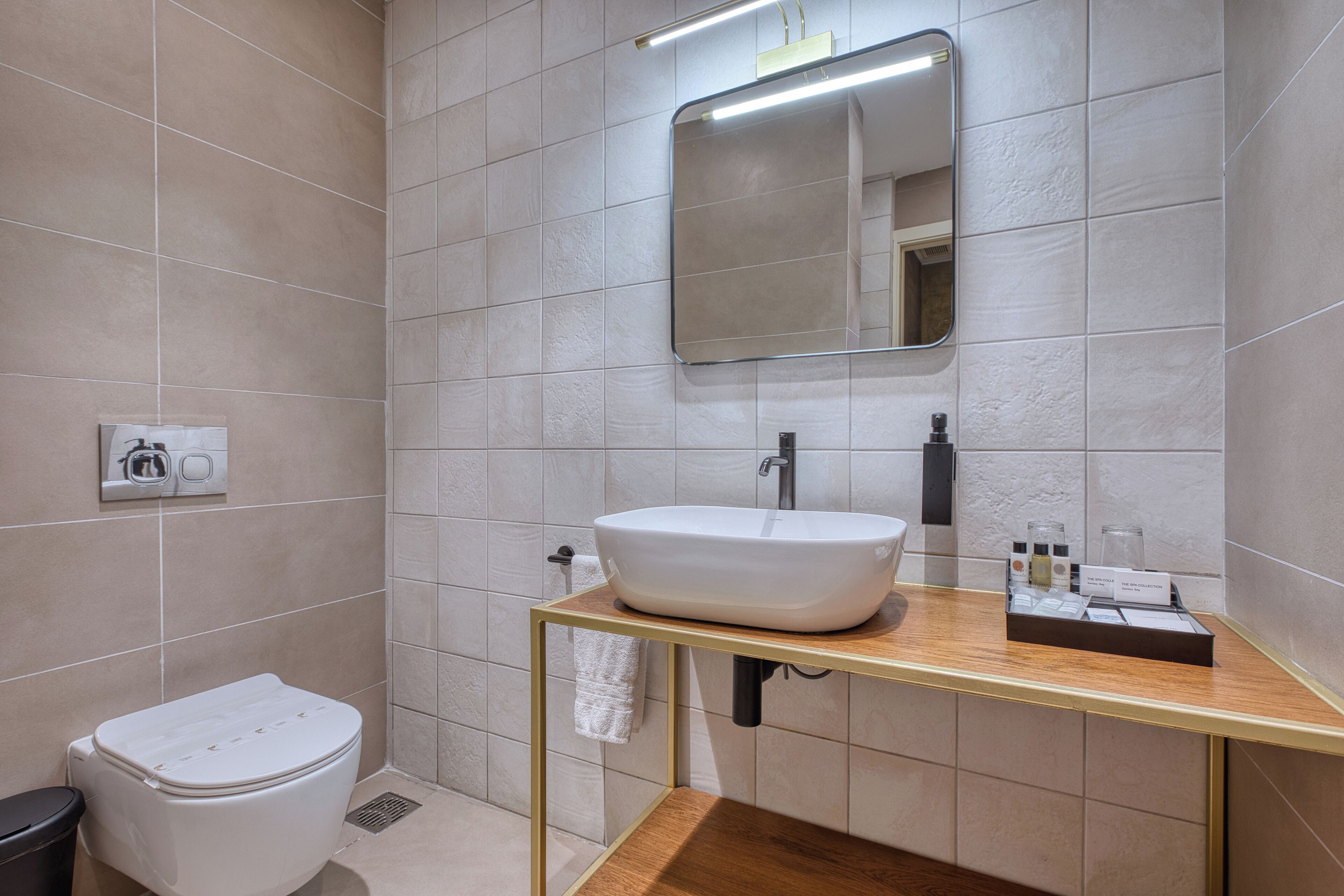 A modern bathroom with a white toilet, a sink with a mirror above it, and a towel hanging on the wall.