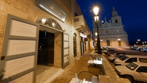 A restaurant with outdoor seating, a signboard listing starters, and a historic church in the background.