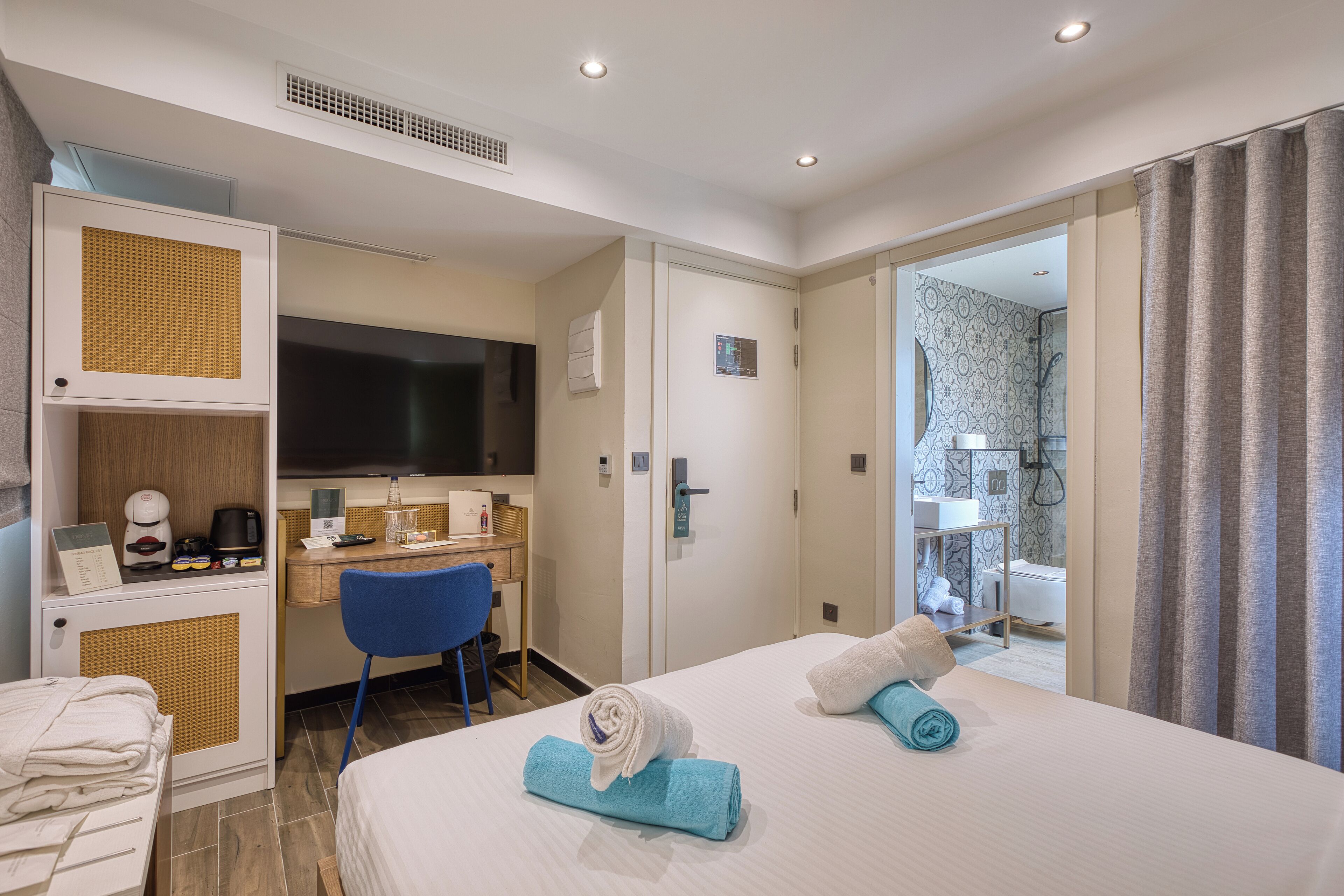 A hotel room with a bed, a desk, a chair, and a shower area.