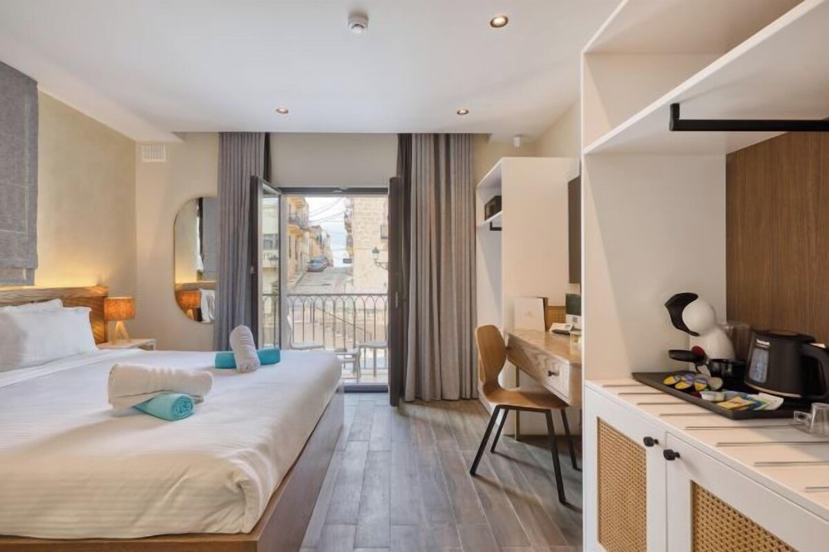 Una habitación de hotel con cama, escritorio y balcón.