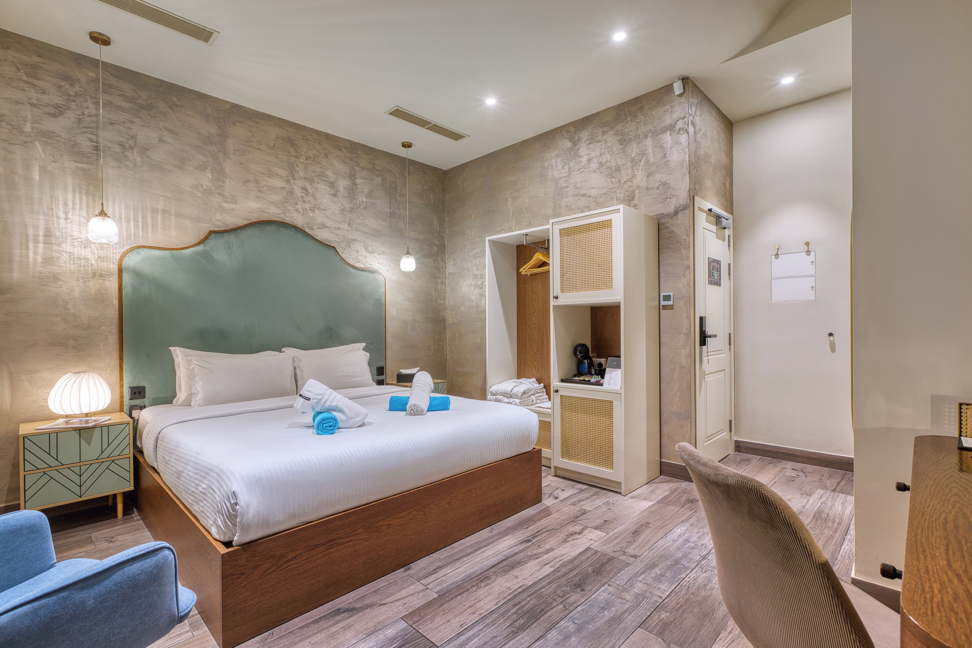 A modern hotel room with a large bed, bedside table, lamp, and a wardrobe with a mirror.
