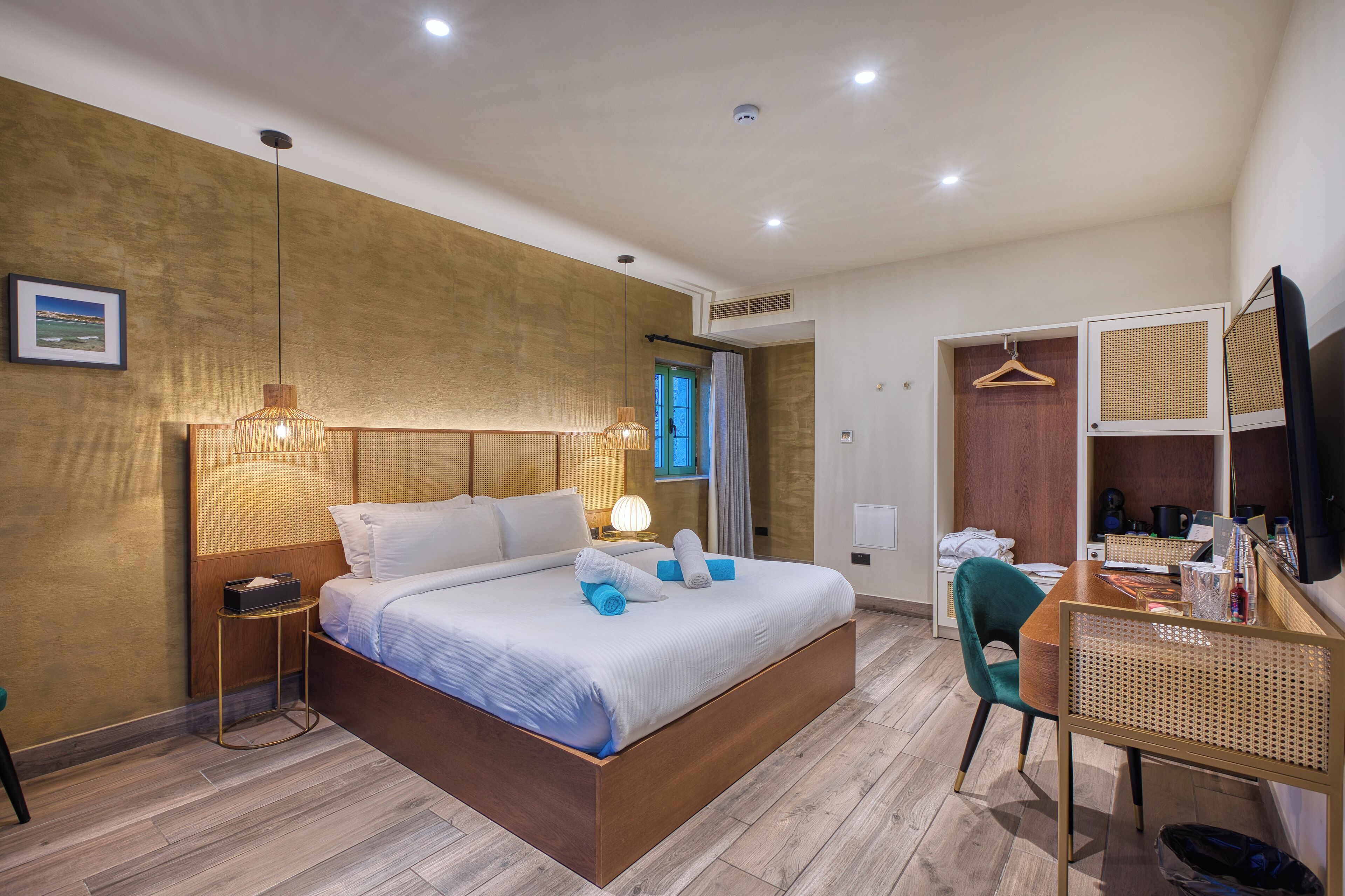 Ein modernes Hotelzimmer mit einem großen Bett, Nachttischlampen, einem Schreibtisch mit Stuhl, einem Kleiderschrank und einem Fernseher.