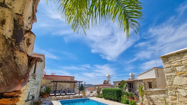 Una piscina de piedra rodeada de plantas en macetas y edificios de piedra.