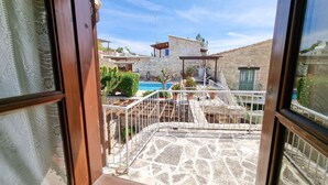 Un patio de piedra con piscina, pérgola y vistas a un edificio de piedra con balcón.