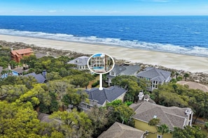 Vista aérea de una zona residencial costera con casas, una playa y una gran estructura circular.