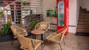 Un espacio interior moderno con mobiliario de mimbre, un refrigerador Coca-Cola y un acuario.