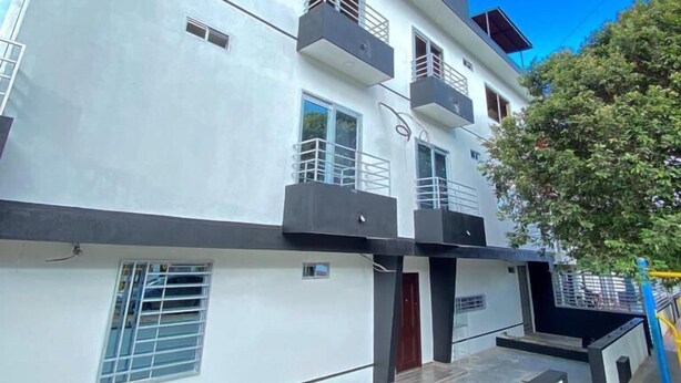 Un moderno edificio de varios pisos con balcones, ventanas grandes y techo plano.