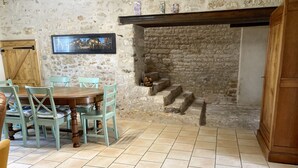 A rustic dining area with a stone wall, wooden door, and a framed picture on the wall.
