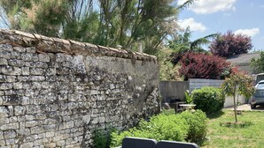An outdoor patio area with wicker furniture, a stone wall, and a view of a residential street.
