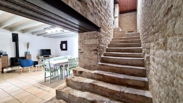 A staircase leading to a lower level, with a dining area visible in the background.
