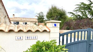 A gated entrance with a sign reading "LA BULLE" and a tiled roof house in the background.