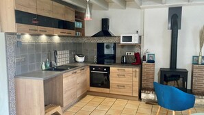 A modern kitchen with wooden cabinets, a built-in oven, a microwave, and a black stove.
