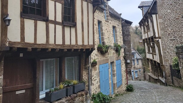 A narrow cobblestone street lined with traditional half-timbered buildings, featuring stone facades and wooden beams. - Maison Médiévale au Cœur de la Vieille Ville de Dinan (Dinan)