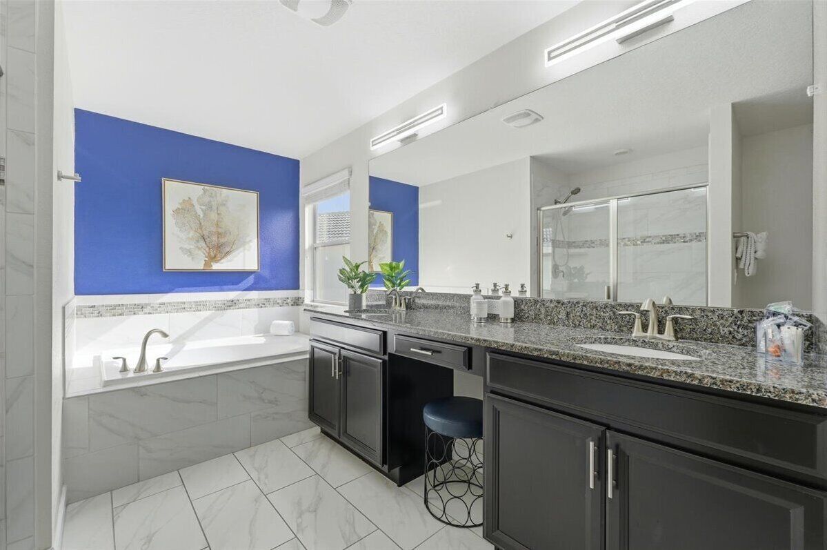 Un baño moderno con un espejo grande, una bañera, un lavabo y una encimera con una planta.