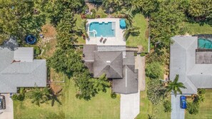 Vista aérea de um bairro residencial com piscina, várias casas e áreas verdes ao redor.