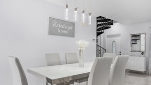 A modern dining area with a white table and chairs, a decorative vase, and a motivational quote on the wall. - Fairview Getaway (Fort Myers)